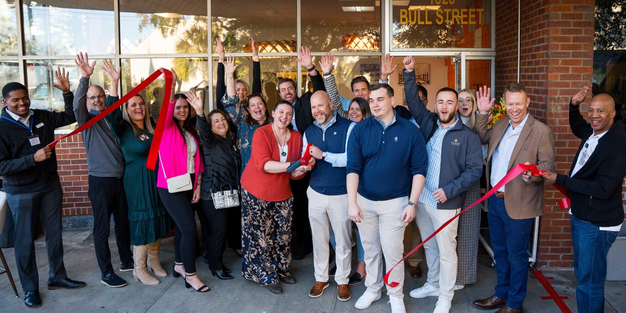 A group of lighting agency team members cut a red ribbon to commemorate expansion into the Savannah, Georgia territory