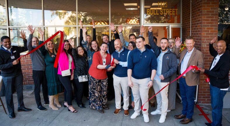 A group of lighting agency team members cut a red ribbon to commemorate expansion into the Savannah, Georgia territory
