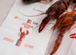 A crawfush is placed next to an invitation for the SESCO Nashville & ORI Crawfish Boil event