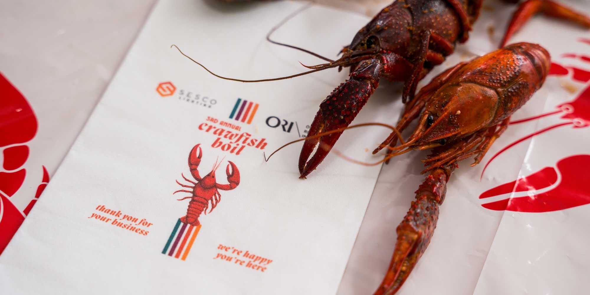 A crawfush is placed next to an invitation for the SESCO Nashville & ORI Crawfish Boil event