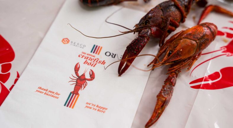 A crawfush is placed next to an invitation for the SESCO Nashville & ORI Crawfish Boil event